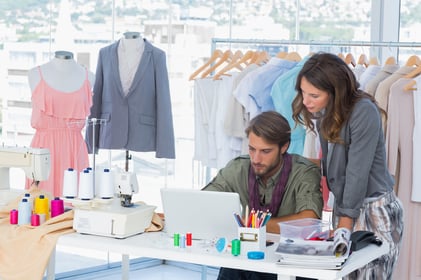 Two fashion designers working on laptop in creative office